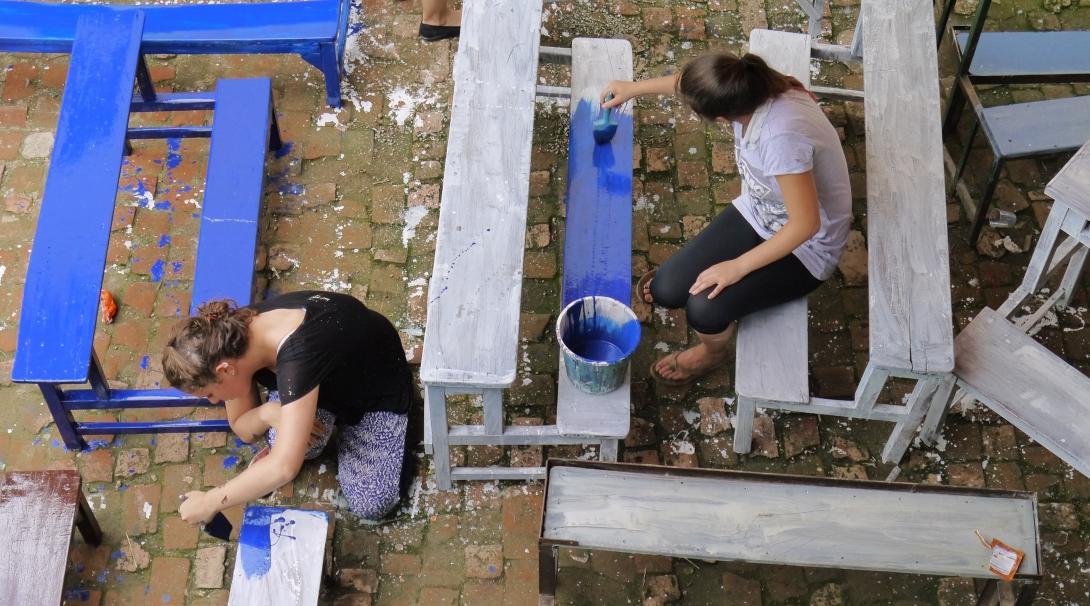 A group of HIV/Aids volunteers in Nepal assist with renovation work at their care placement. Projects Abroad HIV/Aids volunteers in Nepal paint chairs and desks at their Childcare placement.